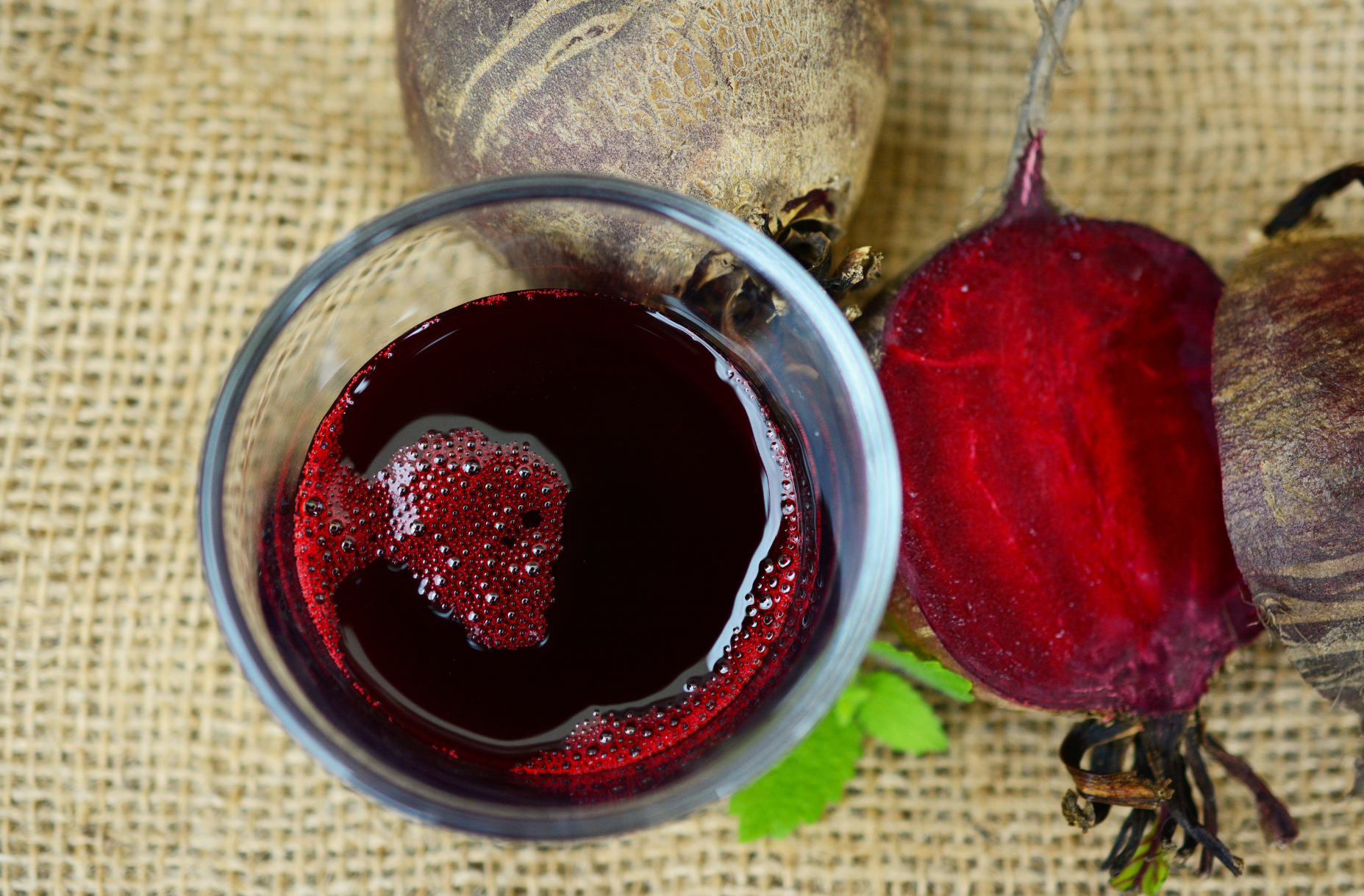 Glass of red beetroot juice with fresh beets on a rustic background