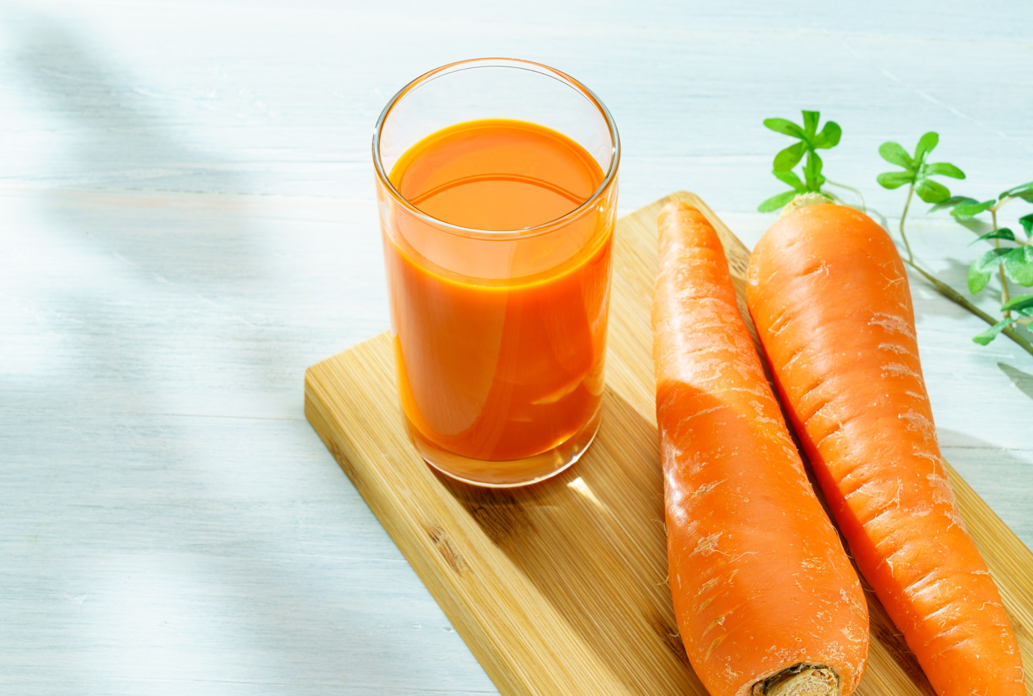 Glass of carrot juice on a wooden board with carrots and a blurred background